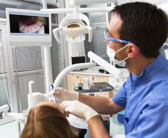 Dentist looking at intraoral photos of teeth while examining patient