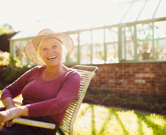 Senior woman sitting outside, smiling brightly