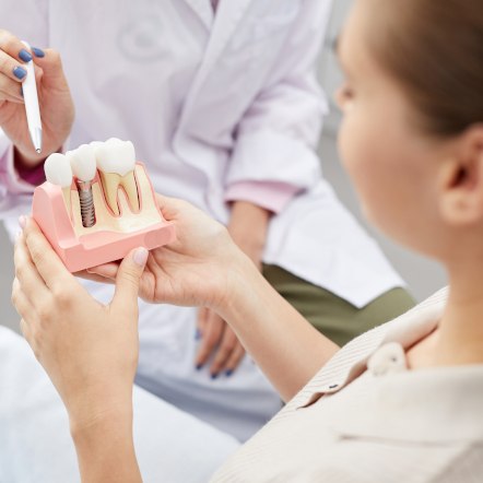 A dental patient holding an enlarged dental implant model