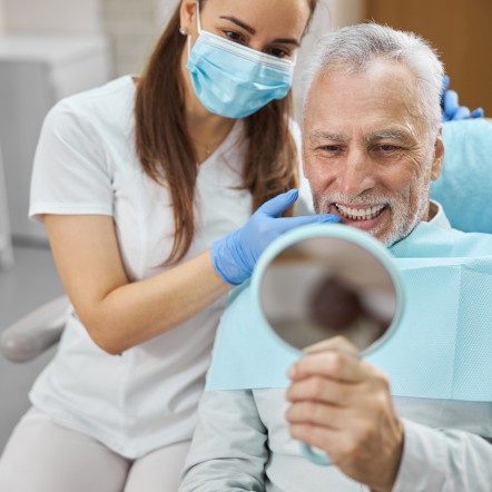 An older man happy with his complete dental implant