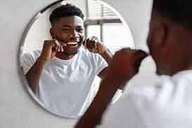 Man smiling while flossing his teeth