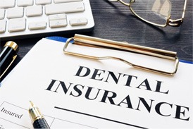 Dental insurance forms on clipboard next to office supplies