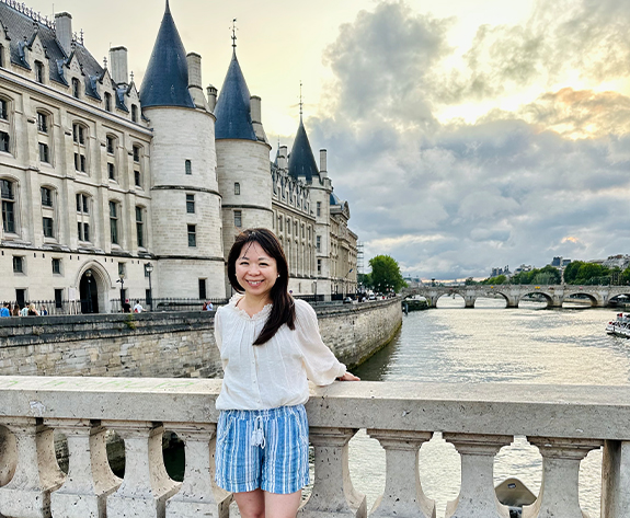 Doctor Bailey smiling on bridge with castle in background