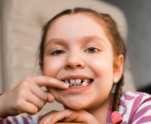 Young girl pointing to traditional braces on her lower teeth