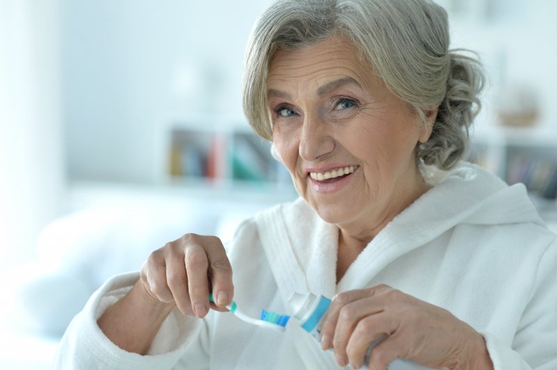 Woman smiling as she prepares to brush her dentures